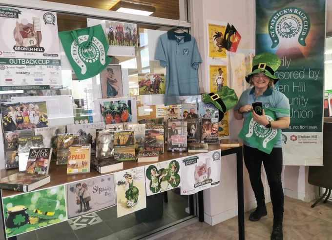 Display of books about racing. Person wearing shamrock hat.