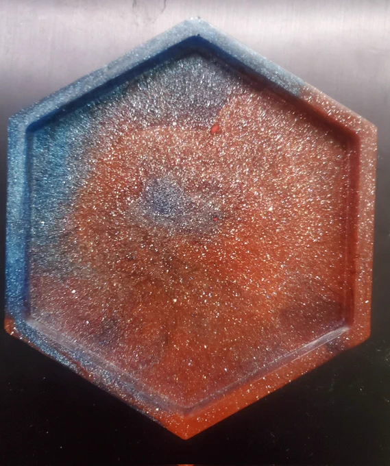 A hexagonal red and blue swirled resin coaster