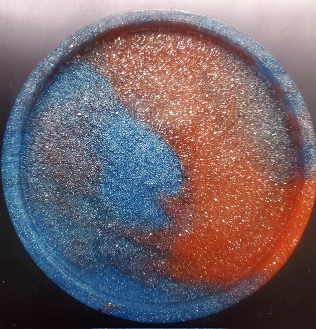 A circular red and blue swirled resin coaster