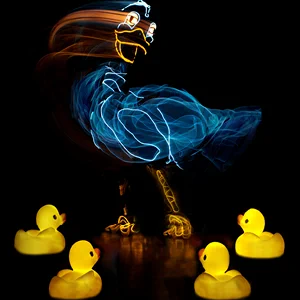 An eletroluminect puppet of a mother duck dances above glowing yellow rubber duckling babies. Photo courtesy of Lightwire Theater. 
