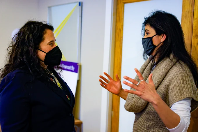 Administrator Guzman listen to a woman gesturing. Both are wearing masks. 