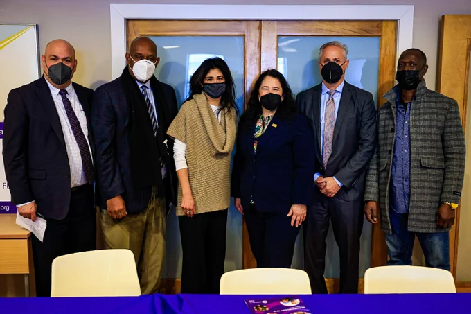 Administrator Guzman stands with 5 other people in front of a door. All are wearing masks. 