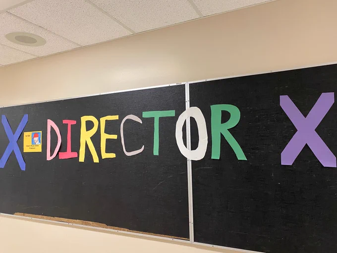 Bulletin board with the words “X Director X” and a photo. 