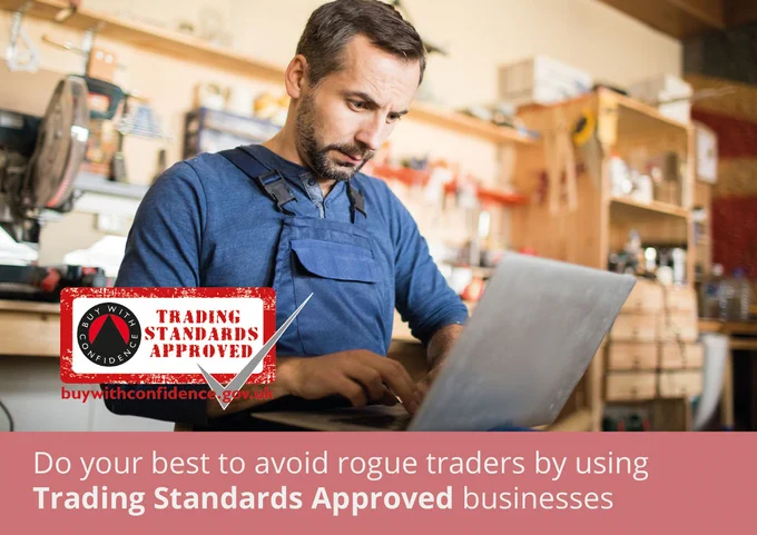 A man in a workshop wearing dungrarees types on his laptop. The caption reads: Do your best to avoid rogue traders by using Trading Standards Approved businesses