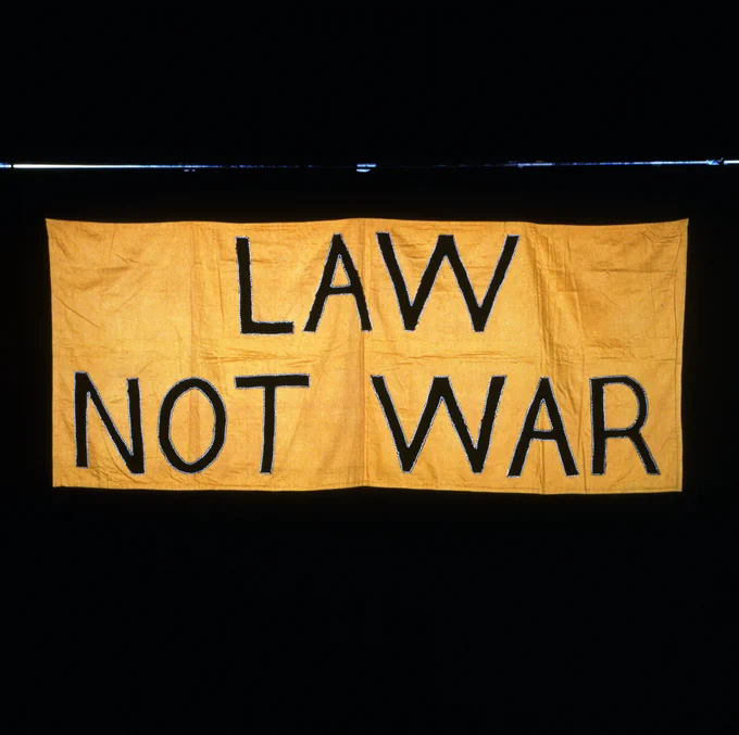 A banner. Gold and black. Includes the text "Law Not War".