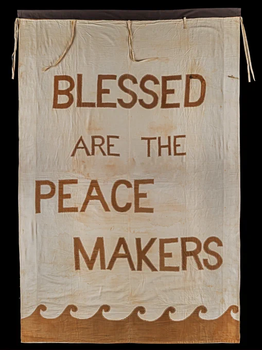 A banner brown and creme in colour. It includes the text "Blessed Are The Peace Makers".