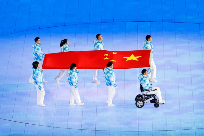 Six Chinese athletes enter the arena holding their national flag