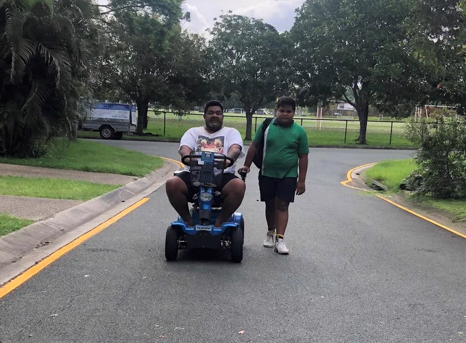Donny outside on his new mobility scooter with one of his children.