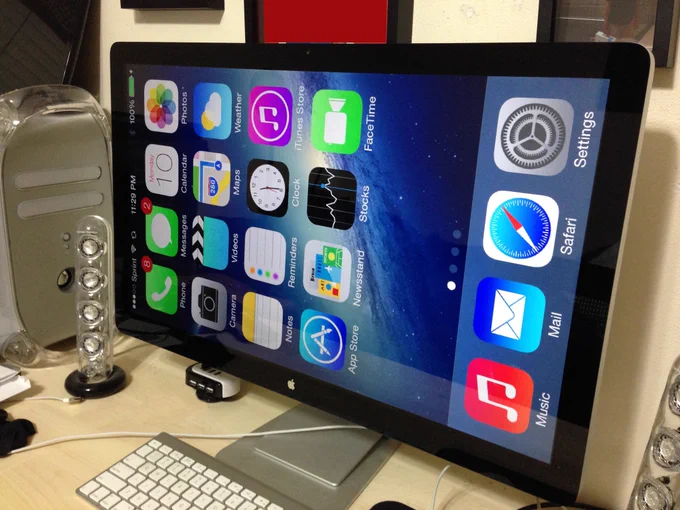 An iPhone Home Screen is mirrored to a 27-inch Apple Cinema Display.