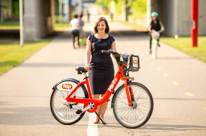 [Image Description: MoGo Founder Lisa Nuszkowski poses with MoGo bikes.]