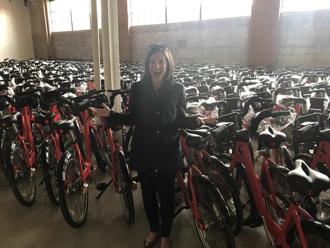 [Image Description: MoGo Founder Lisa Nuszkowski poses with MoGo bikes.]