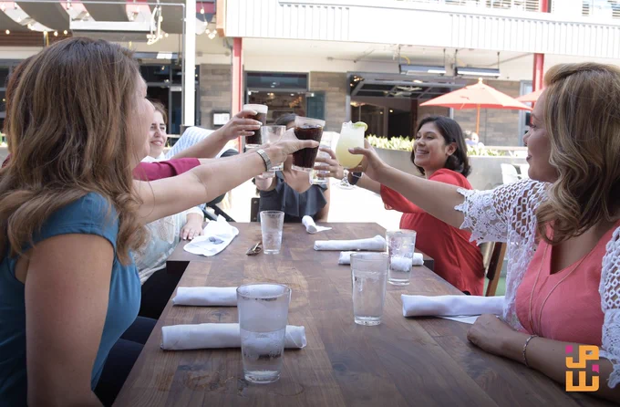 JPW female leaders and employees do a cheers at a table.