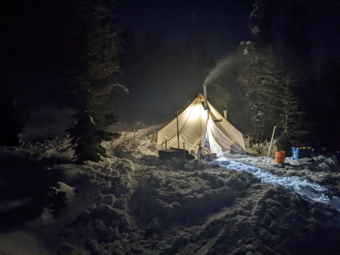 Glowing canvas tent at night in the snow