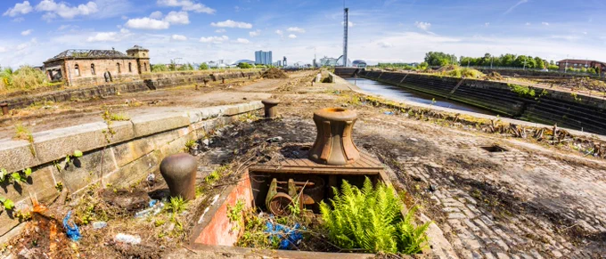 GALLANT website splash photo of a Glasgow cityscape with derelict canal land in foreground livened up by some growing greenery.
