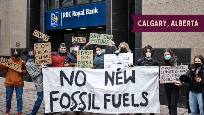 A group of activists stand in front of an RBC branch with a banner that reads "No new fossil fuels". They hold various signs that read "divest", "stop funding climate change", "save our future", "divest from fossil fuels", and "we cant tackle climate change without tackling fossil fuels". Yellow text on a red label at the top right reads "Calgary, Alberta"
