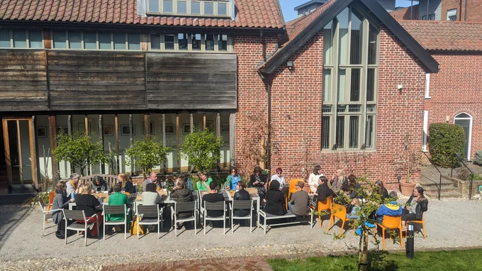 The CPC cohort sit in the Dragon Hall garden, sat around a large table eating lunch