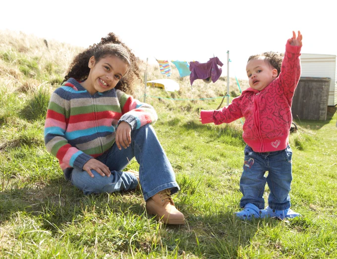 A young girl and her baby sister play in the sunshine.