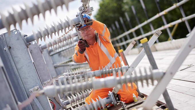 An engineer installs overhead electric wires above the railway.