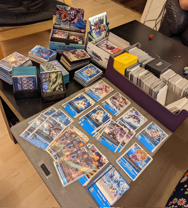 Es liegen sehr viele Digimon Sammelkarten auf einem Tisch.