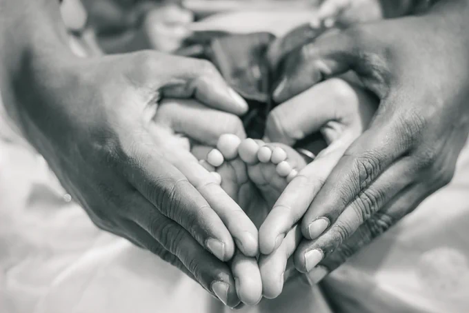 Baby feet with two adult hands