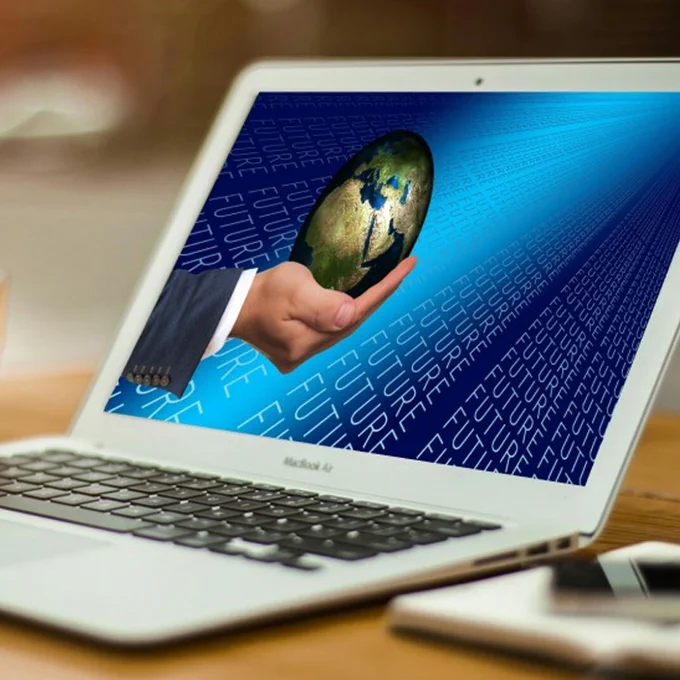 A laptop with an image of a hand holding a globe with a background of the word future.