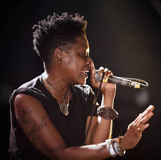 📷 of Shirlette Ammons singing into a microphone, her face glowing in the light.