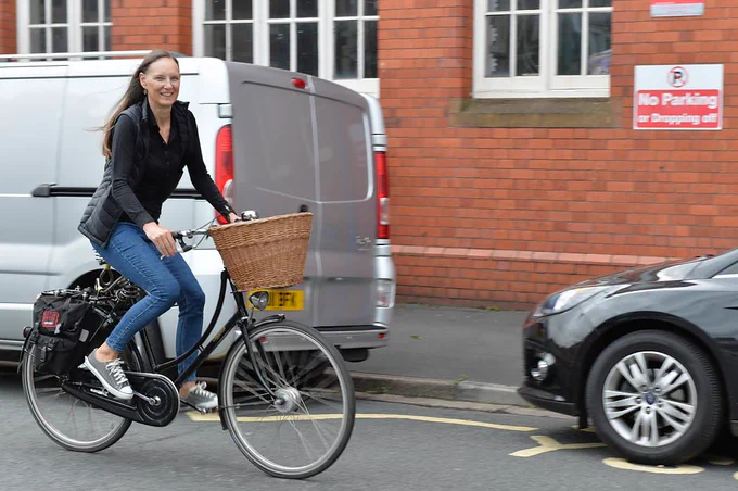 Female cyclist riding past cars