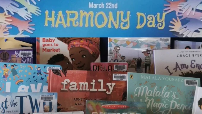 Pile of books with poster that says Harmony Day