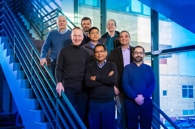 Eight University at Buffalo researchers standing on a staircase in the Natural Sciences Complex. Bottom row, from left: Paras Prasad and Luis Velarde. Middle row, from left: Jonathan Bird, co-principal investigator, Hao Zeng and Mark Swihart. Top row, from left: Andrey Kuzmin, Vasili Perebeinos and Alexander Baev. Credit: Douglas Levere / University at Buffalo
