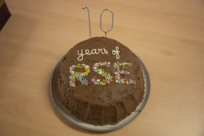 A chocolate cake with buttercream frosting decorated with sparklers and sprinkles reading "10 Years of RSE"