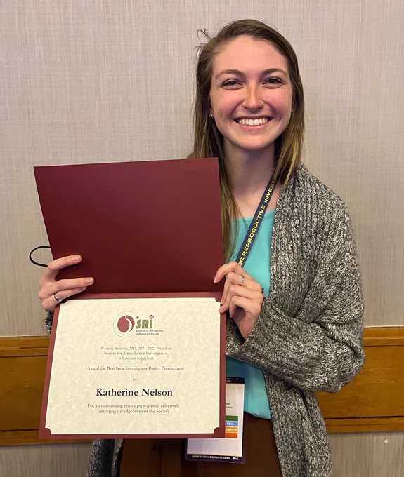 PhD Candidate Katie Nelson displays her award for Best New Investigator Poster Presentation at the Science in the Service of Women's Health annual meeting. The award is for an outstanding poster presentation effectively furthering the objectives of the Society. Hooray, Katie!