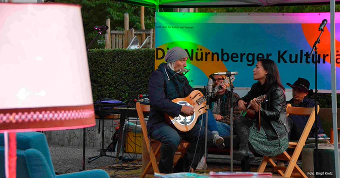 Ein Gitarrist und eine Gitarristin spielen auf dem Platz der Deutschen Einheit in Nürnberg