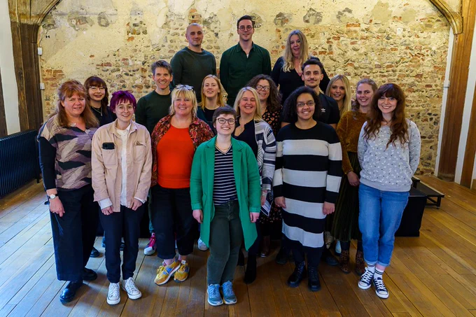 16 Emerging Leaders pose for the camera, smiling against the backdrop of Dragon Hall