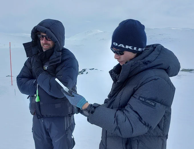Hans-Christian Steen-Larsen keeps a cable warm inside his jacket, while Geunwoo Lee holds a temperature sensor in his hands