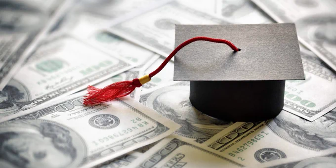 A graduation cap is sitting on top of $100 bills