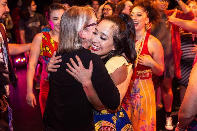 Director Sharon Moore and CONTRA-TIEMPO dancer Jannet Galdamez embracing at a post-show dance party, Fall 2019. Photo by: Robert Davezac