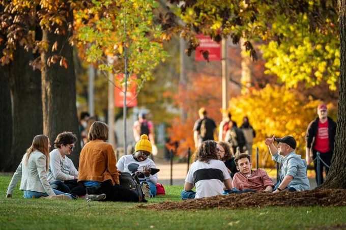 Students sitting in the grass during the fall.
