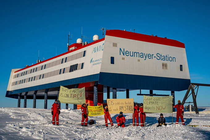 Menschen mit #Klimastreik-Transparenten vor der Neumayer-Station in der Antarktis
