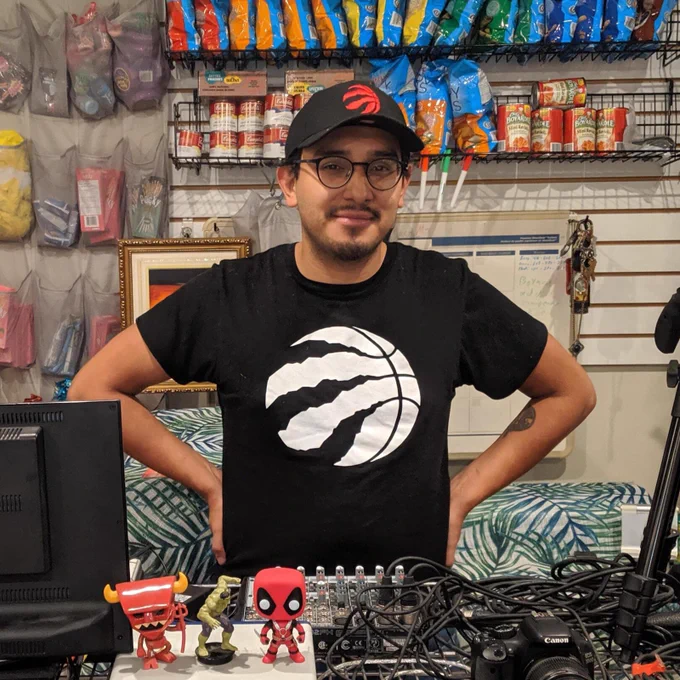 Enzo Carletti stands behind the counter at his business SnackMe, which delivered snack packages across the GTA. He’s wearing a Raptors shirt and hat