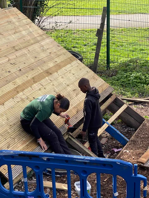 Staff member looks at the work while a young boy looks on
