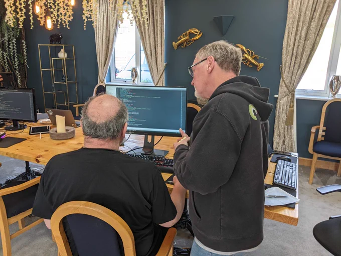 Paul looking over Chris' shoulder at code on Chris' monitor