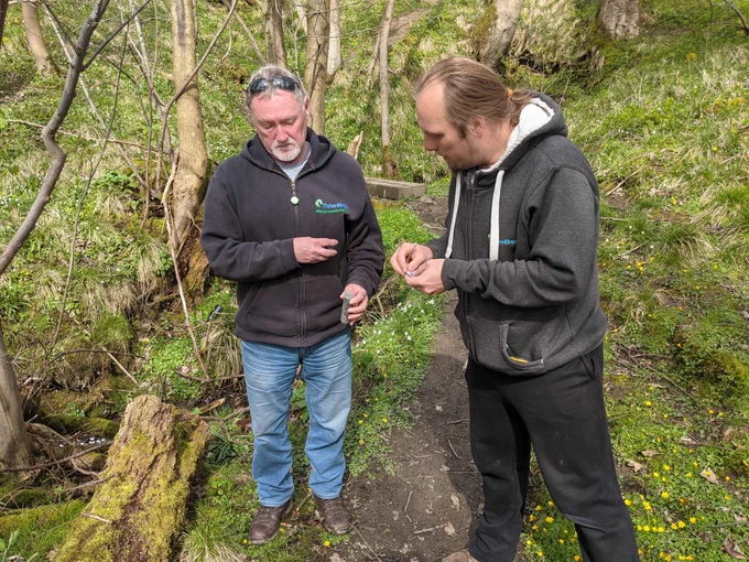 Dan adding our entry into the geocache log, and Paul holding the geocache container that we found