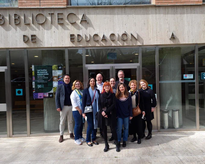 Ten happy people from a European project standing in front of the UNED library building in Madrid