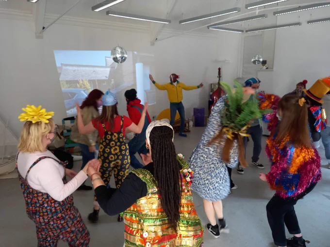 A group of people in costumes dancing in front of a projected video.