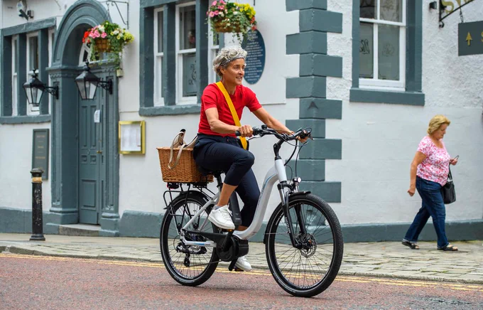 Woman riding e-bike with basket through town centre