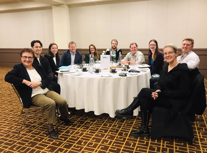 This is a picture of some of the Board Members of AIPS and some of the team members. Everyone is sitting around a round table.