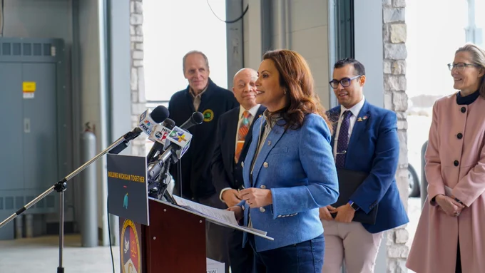 Michigan Governor Gretchen Whitmer stands at a podium at a press conference.