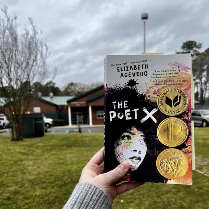 The book The Poet X is pictured with the Merrimac Center in the background. 