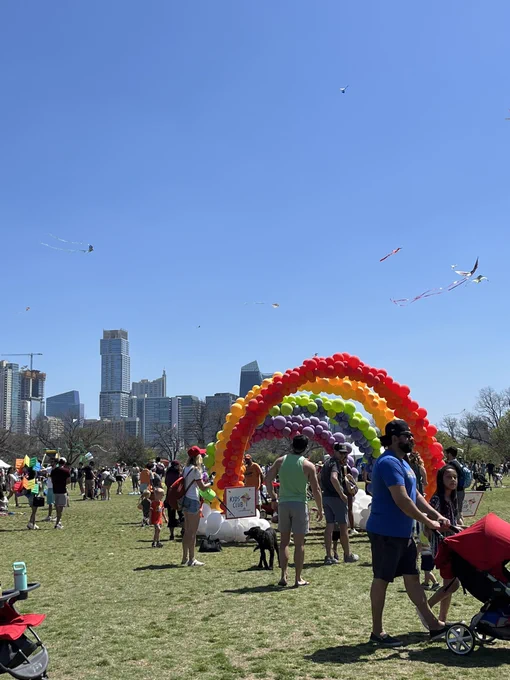 Austin skyline behind park full of people flying kites