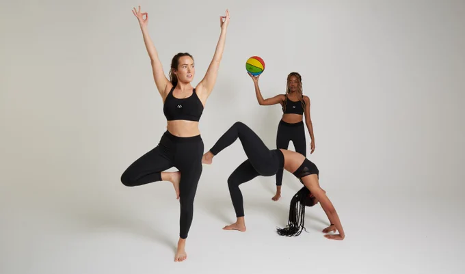 Three women all in black sports bras and black leggings completing different exercised in front of a pale grey background
